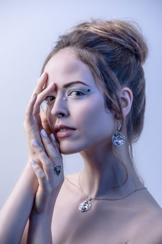 Editorial beauty portrait of a woman with an updo and delicate face jewels, photographed by Art by Light.