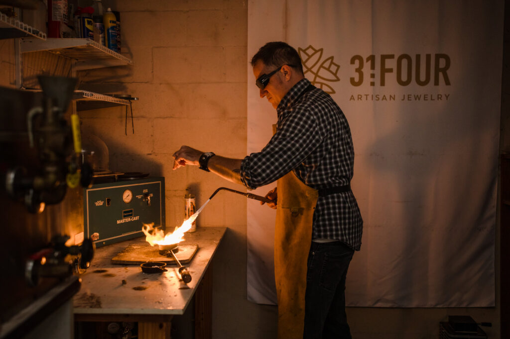 Brand storytelling photograph of a craftsman working at a torch-lit workbench, by Art by Light Photography.